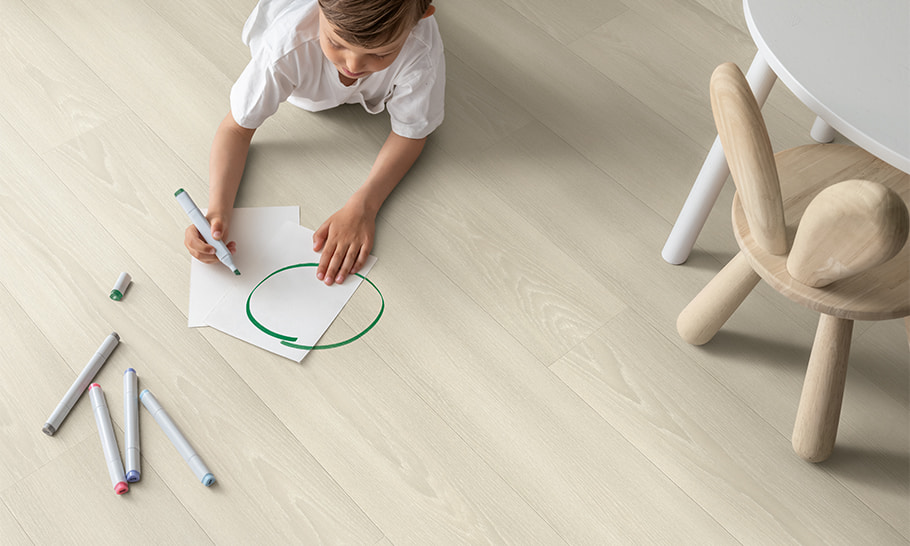kid drawing while laying on a white laminate floor